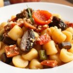 "Deliziosi gnocchi di erbette al burro con speck croccante e nocciole, piatto autunnale ideale per cene in compagnia."