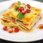 ALT: "Lasagne con fave fresche e speck, un primo piatto primaverile ricco di sapori."