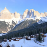 "Panorama delle Dolomiti con rifugi accoglienti, piste da sci e borghi storici di San Martino e Primiero."